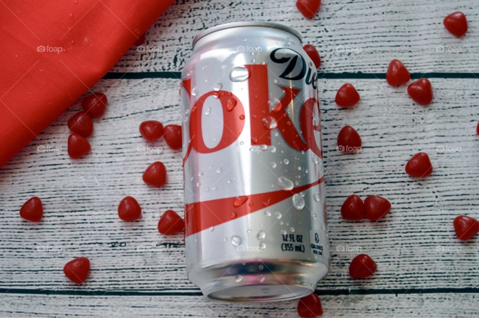 Hey can of Diet Coke with candy hearts on a white rustic background