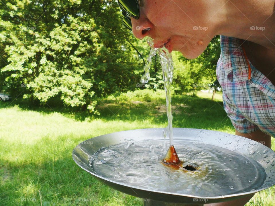 The girl is drinking water on a hot summer day