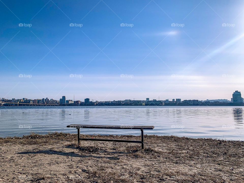 A bench near the river, urban view across the river 