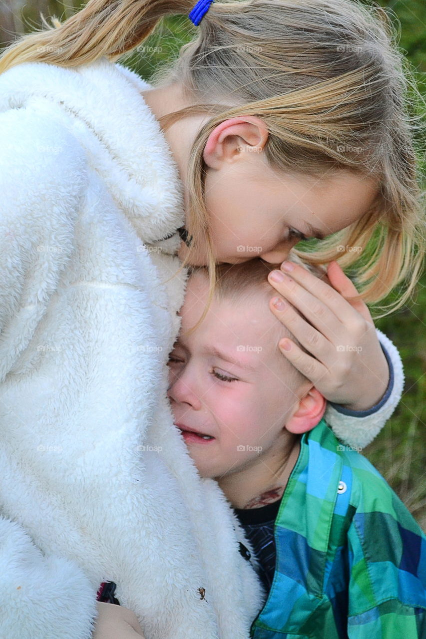 Crying boy gets comfort from big sister