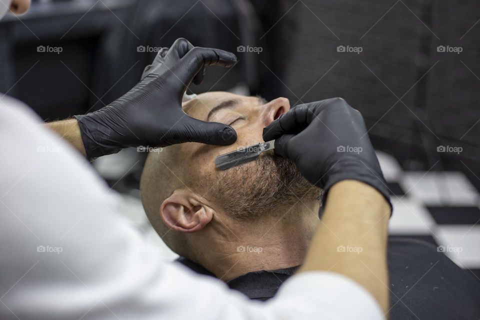 Barber shaving client with the straight razor