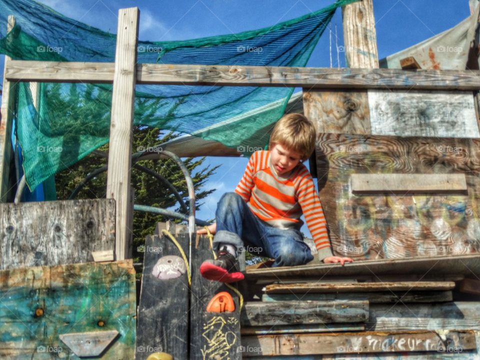 Young Boy Playing In His Treehouse. Summertime Backyard Fun
