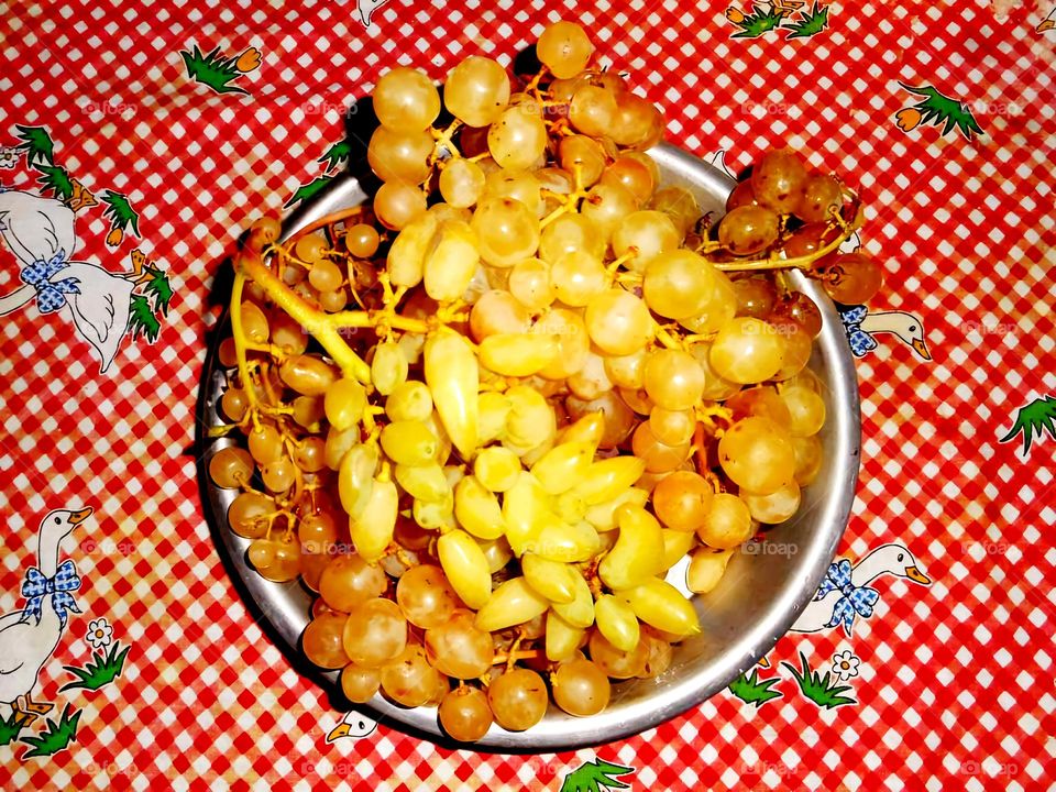 White table grapes served in a tray on a table covered with red and white checkered tablecloth