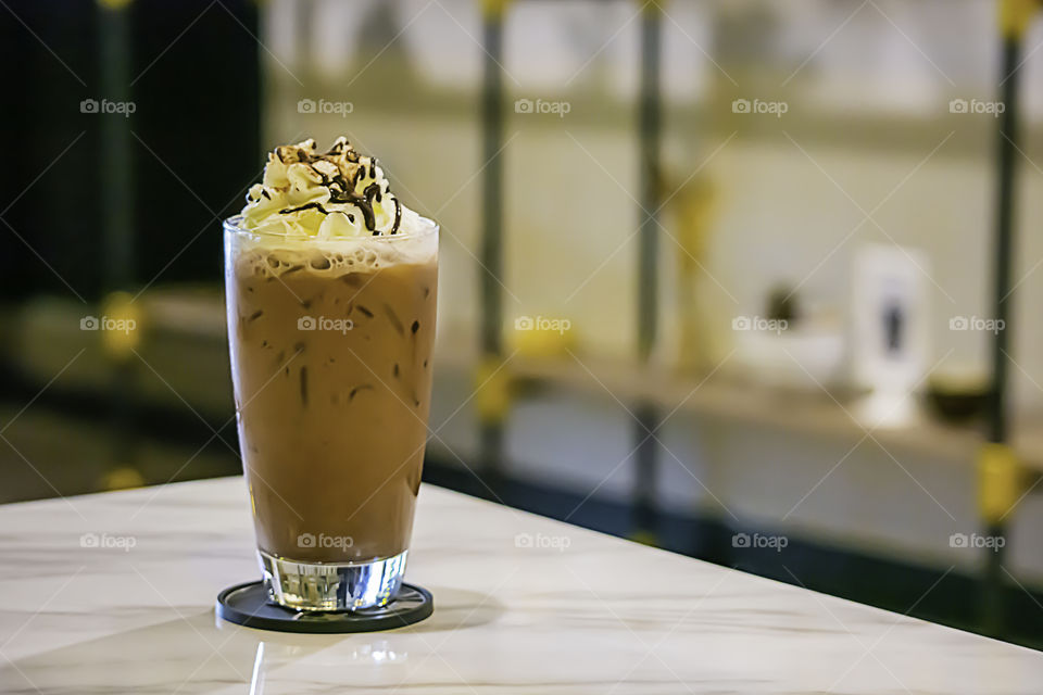 Iced cocoa put whipped cream in a glass on the table.