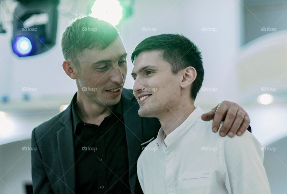 Two handsome, happy, young Caucasian guys communicate with each other, close-up side view.