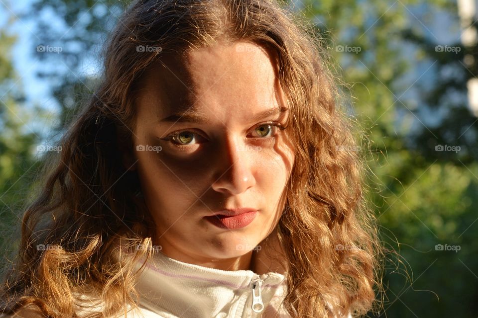 brunette girl beautiful portrait close up in sunlight outdoor green background