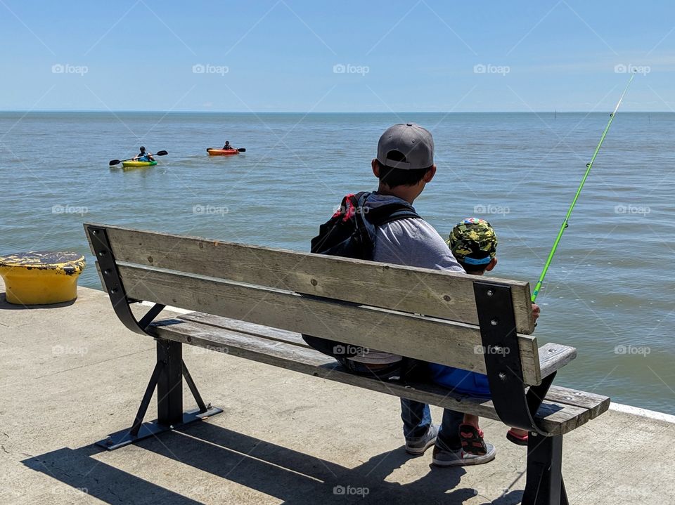 Father and son watch kayakers while fishing!