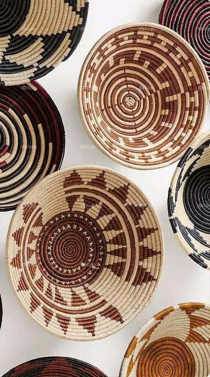 The image shows a group of hand -made dishes of wicker, decorated with colored embroideries with beautiful floral shapes, and is elegantly displayed in a warm corner that combines heritage and beauty, which gives the place an artistic spirit and attr