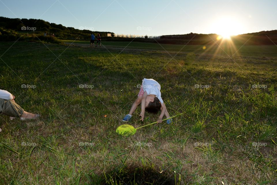 a boy playing in the grass in the field during the sunset