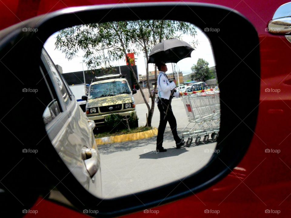 reflection of a security guard through a sideview mirror