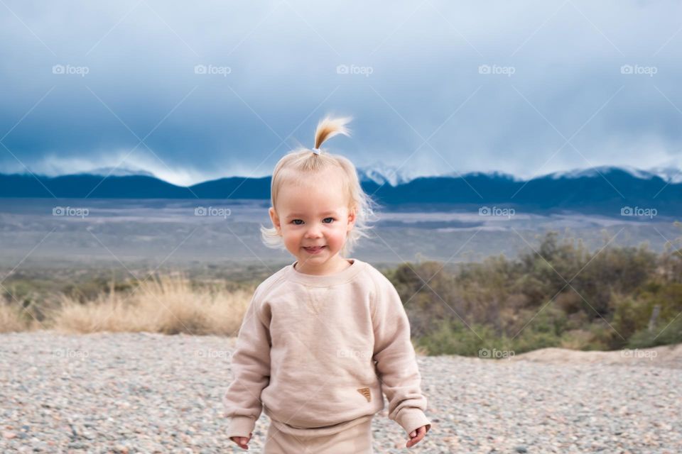 Smiling baby toddler with mountains on the background