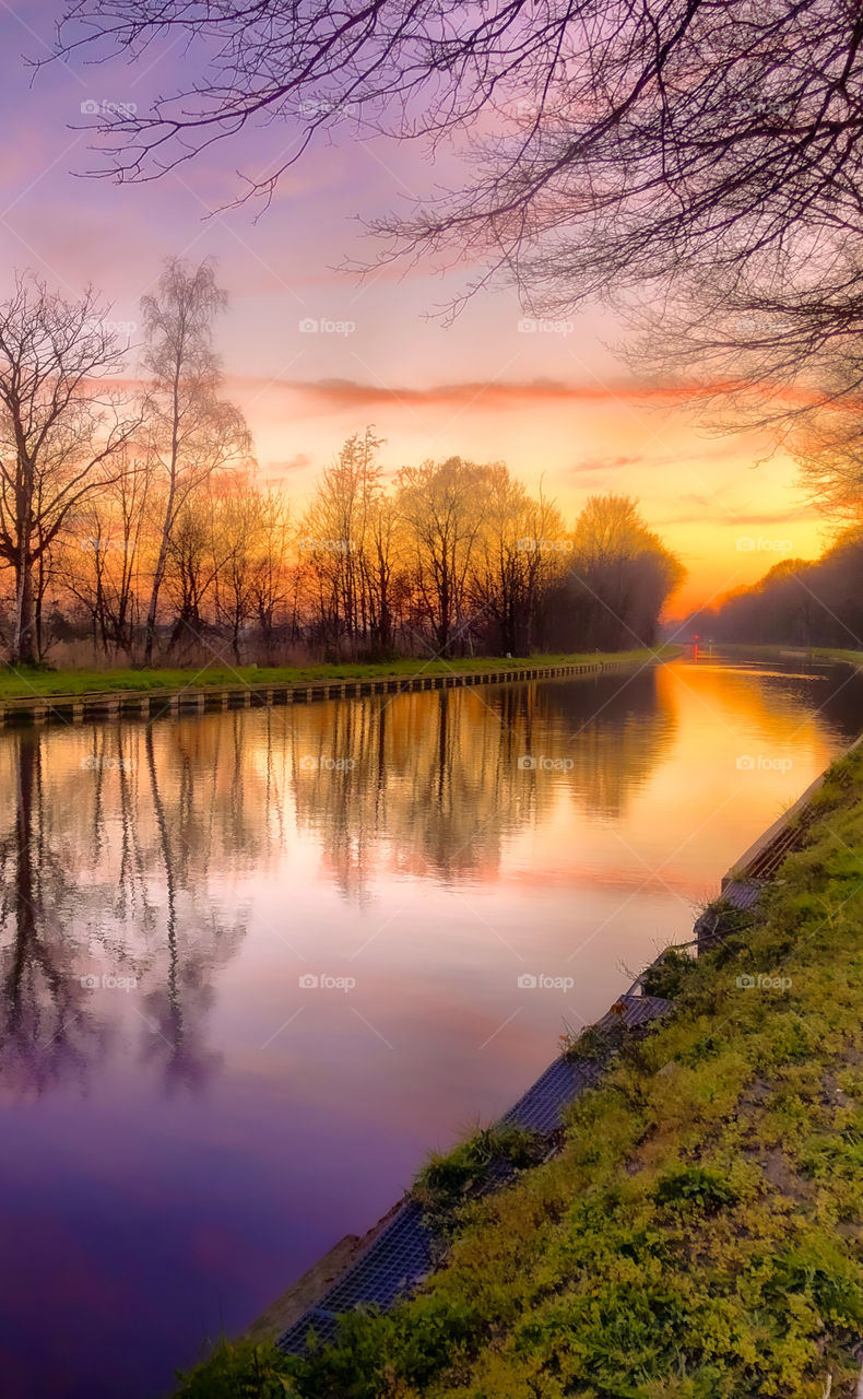 Beautiful pastel colored sky over a rural countryside river landscape, with the soft sunset reflected on the water