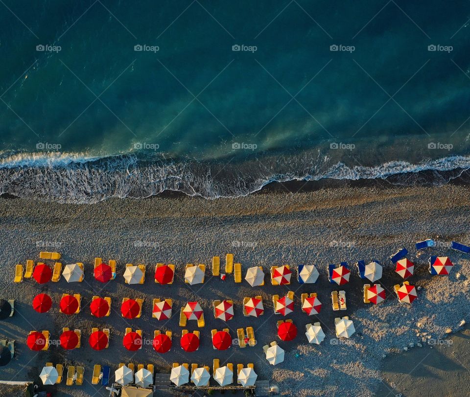 Aerial view of colourful sunbeds and beach 
