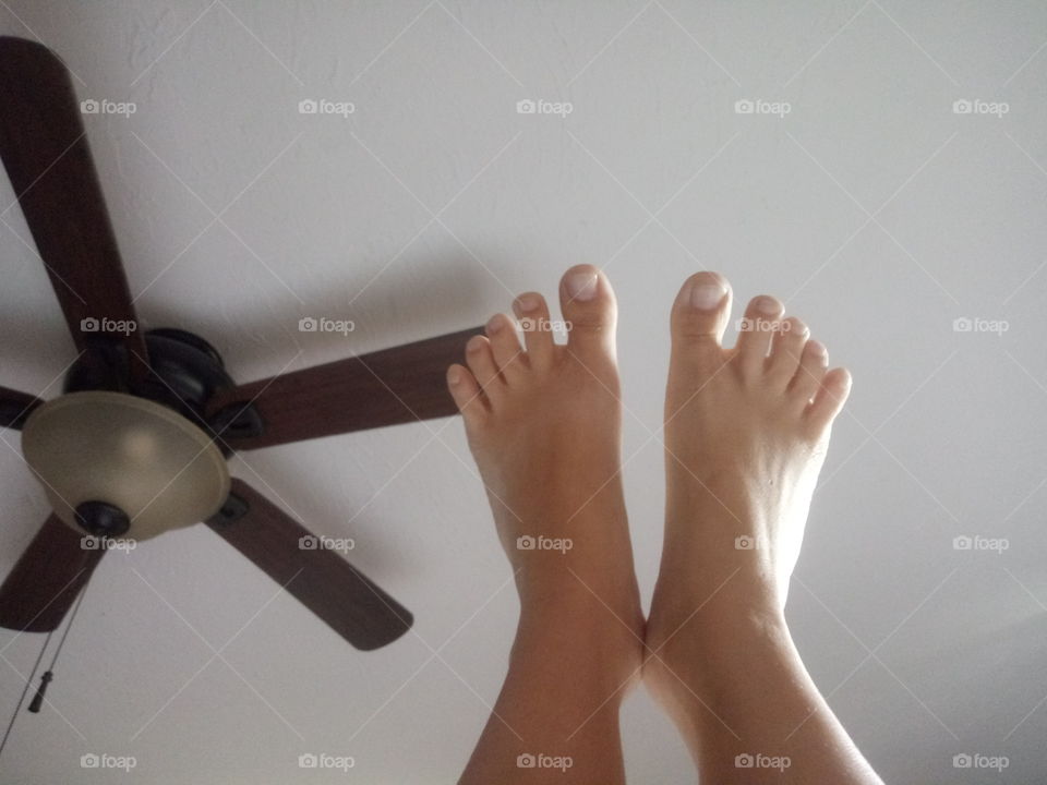 two caucasian small female feet pointed towards the white ceiling