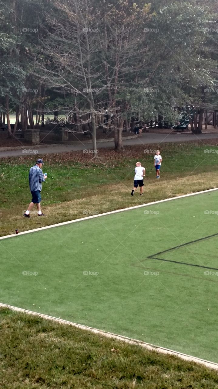 papaw and grand kids playing catch the football in the local park