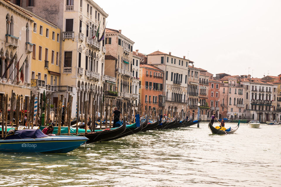 Gondolas moored in river with buildings in background