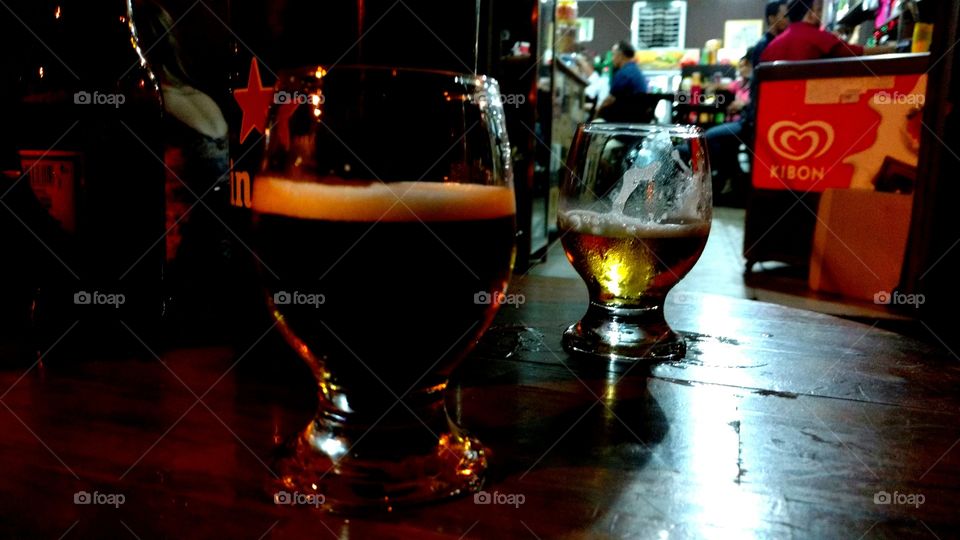 Taças com cervejas espumantes em mesa de um bar.