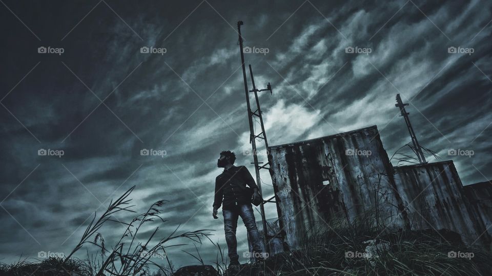 Man standing on grass against storm cloud