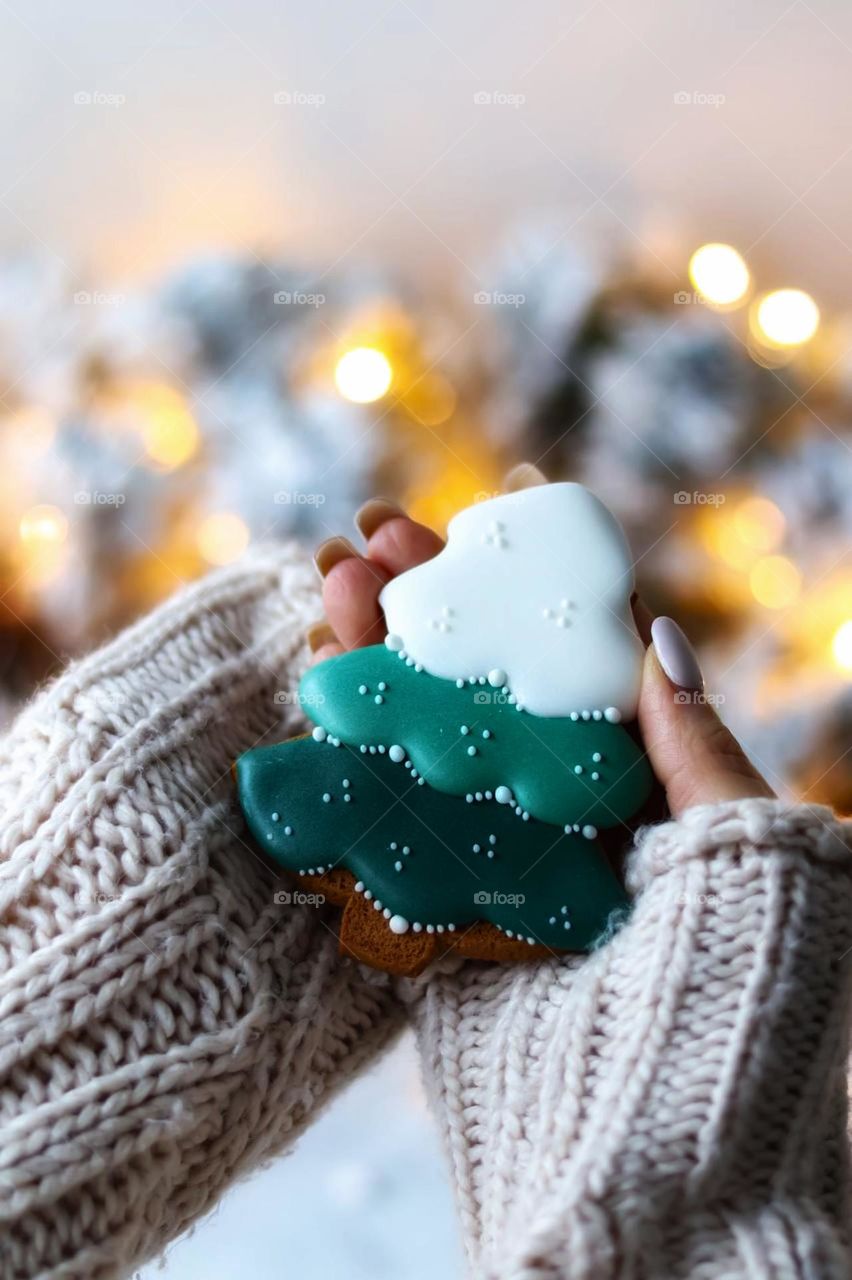 New Year's baking. A woman holding a gingerbread gingerbread in the form of a green Christmas tree