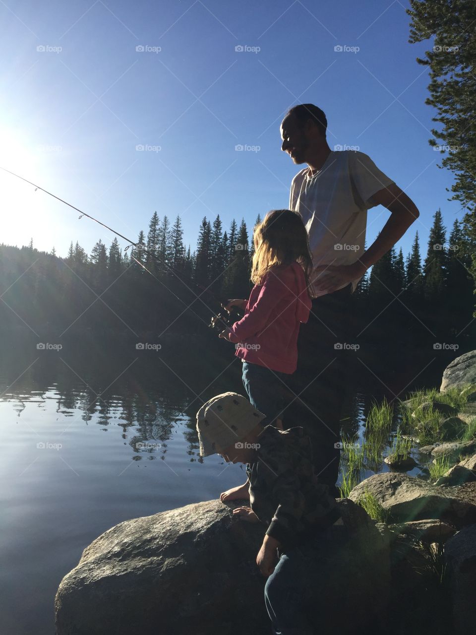 Father fishing with children at sunset