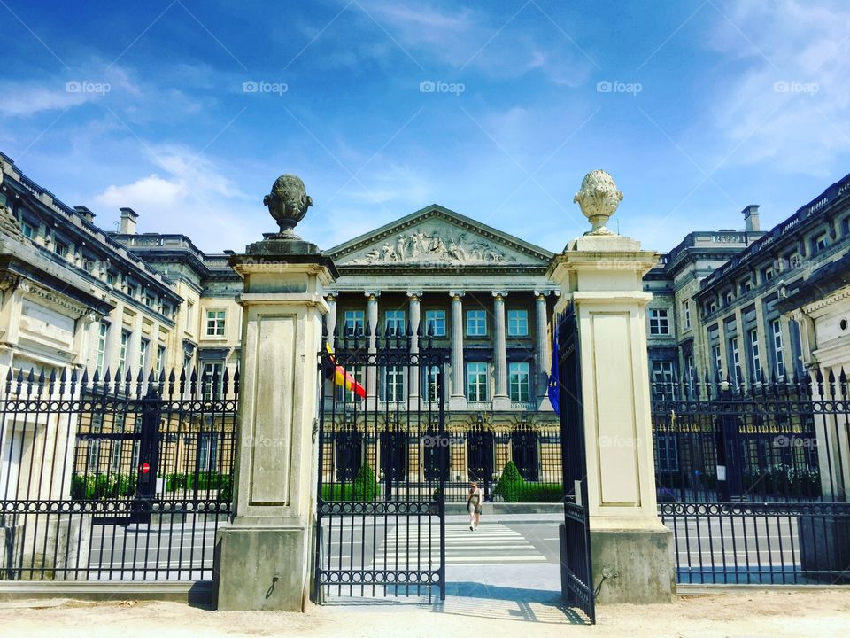 The Belgian house of the federal parliament in the wetstraat or rue de la loi in Brussels on a sunny day, while an older unrecognizable woman is crossing the street.