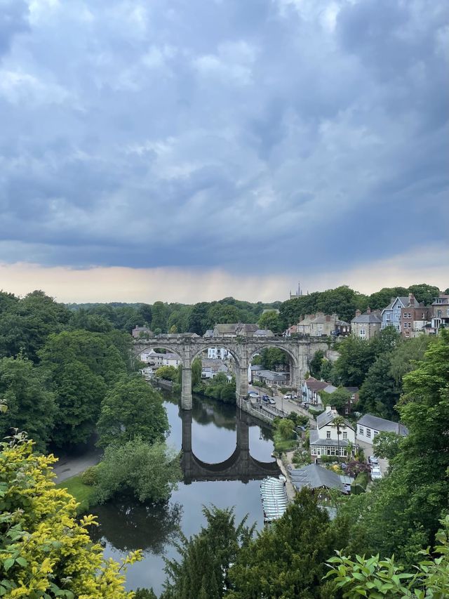 A river runs beneath a stone bridge in the Yorkshire town of Knaresborough, June 2022.