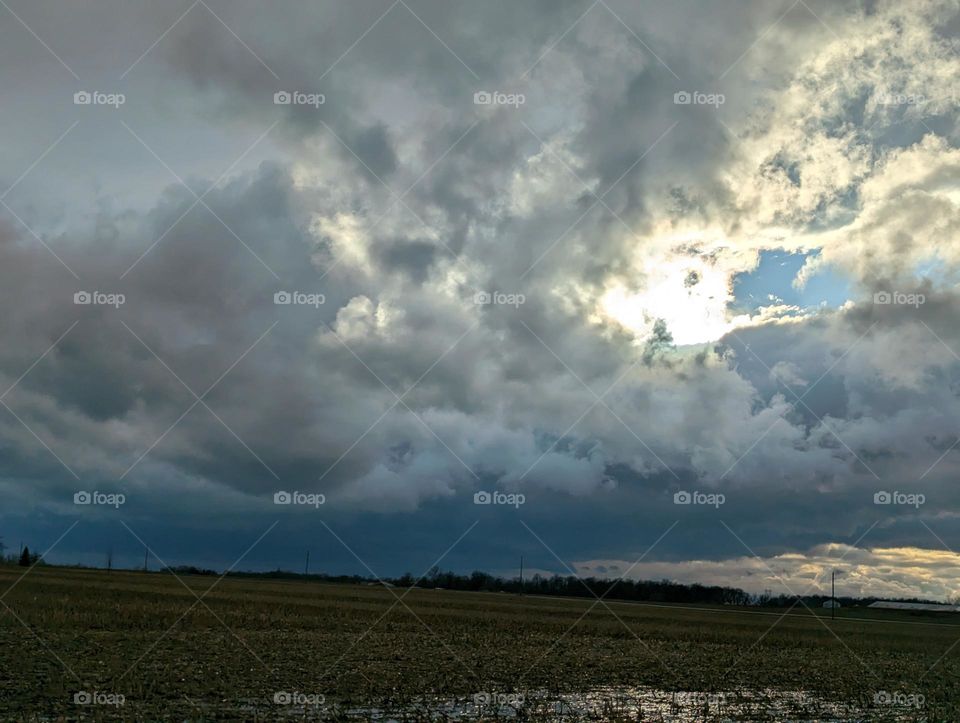 Severe weather clouds over fields and trees.