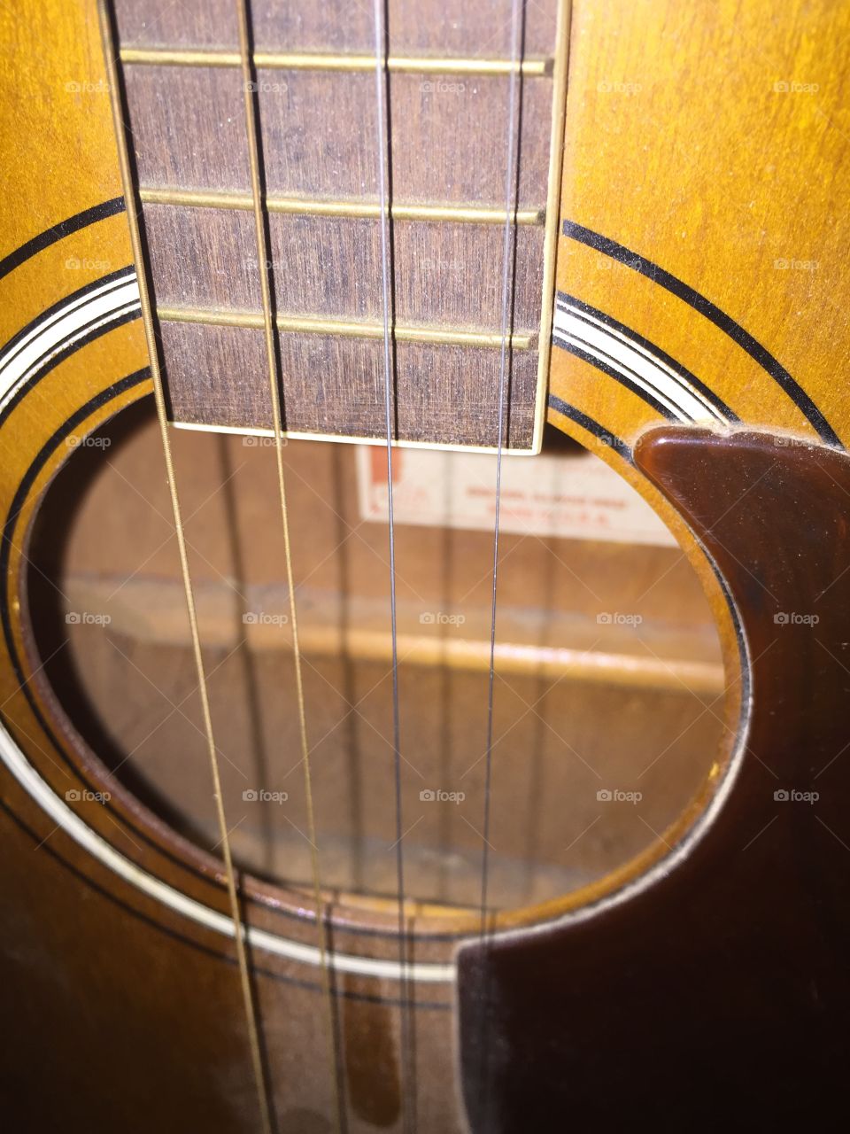 A four string guitar way up close, showing sound hole and strings.