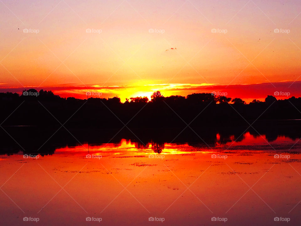Symmetrical orange sunset above the lake 