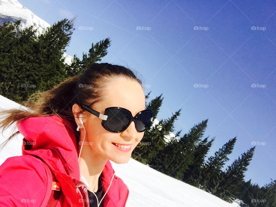 Smiling woman with sunglasses dressed in pink ski costume  with snowy mountains in the background