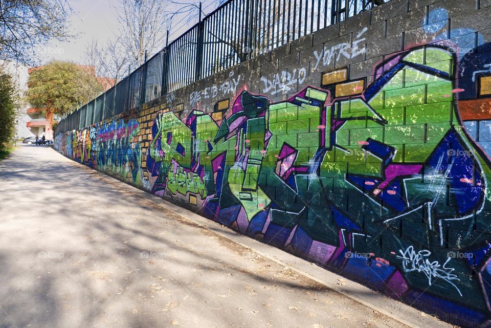 Colorful abstract graffiti and lettering on the brick wall by the path in Krejcarek park in Prague, Zizkov.
