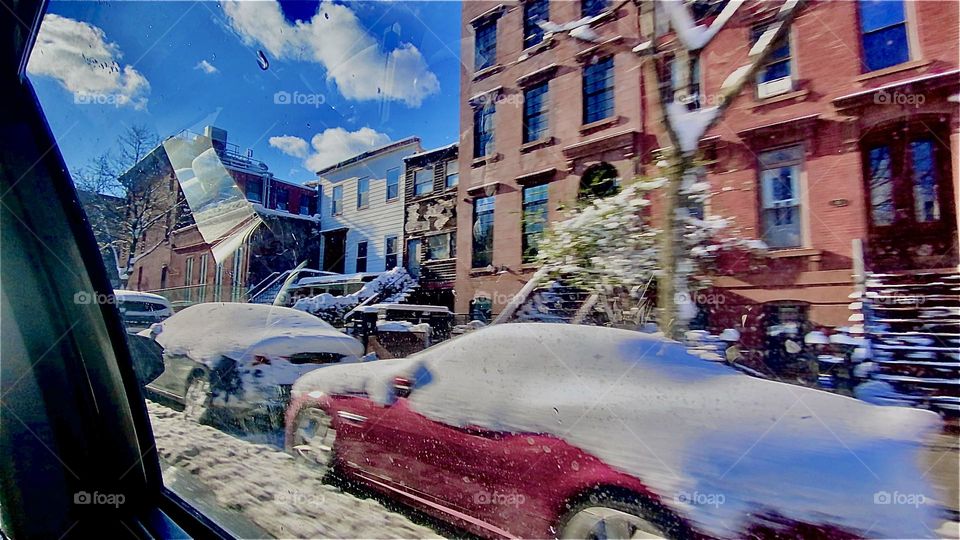 A parked red car covered with snow half a foot high over its roof, windows and down the rear end as well as all over the hubcaps and the front of the vehicle. Winter arrived late on January 6th, 2022. Hypnotic Productions