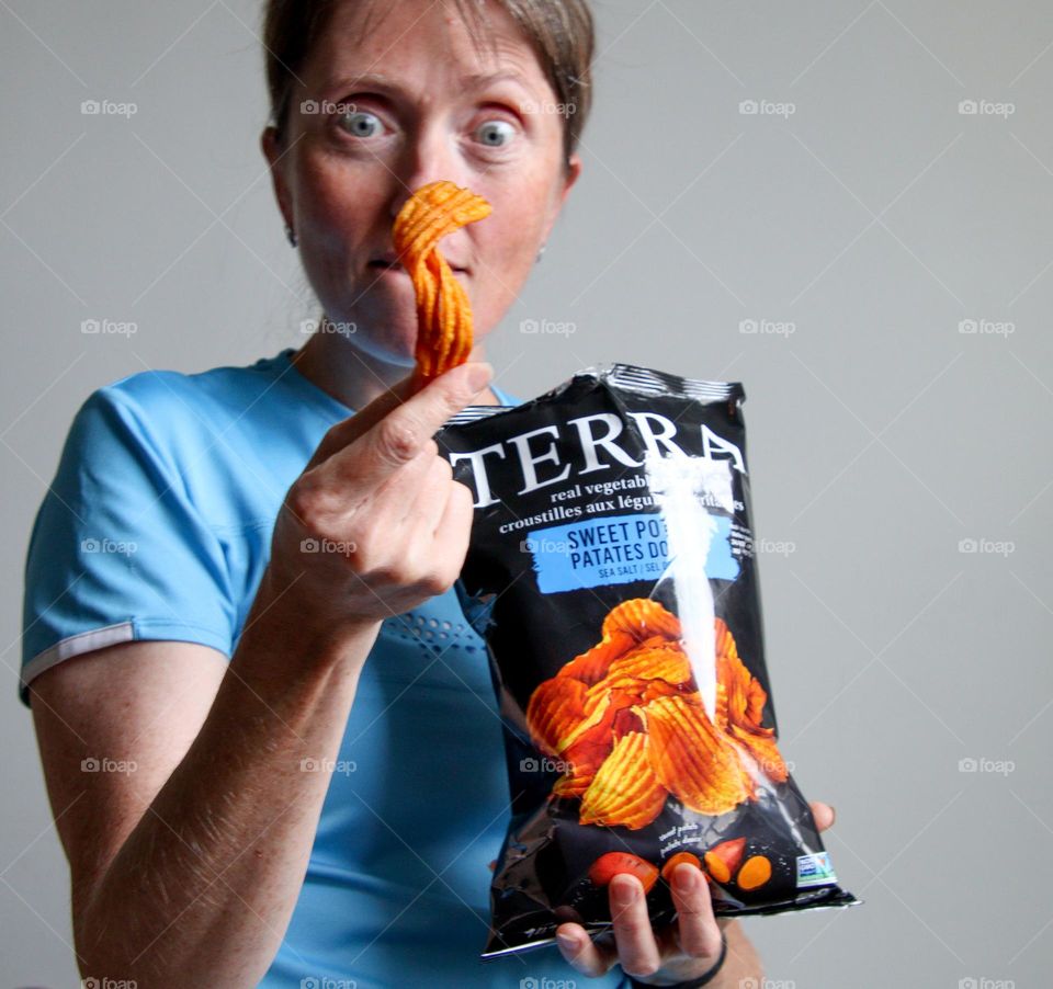 White middle-aged woman with a bag of chips is fooling around