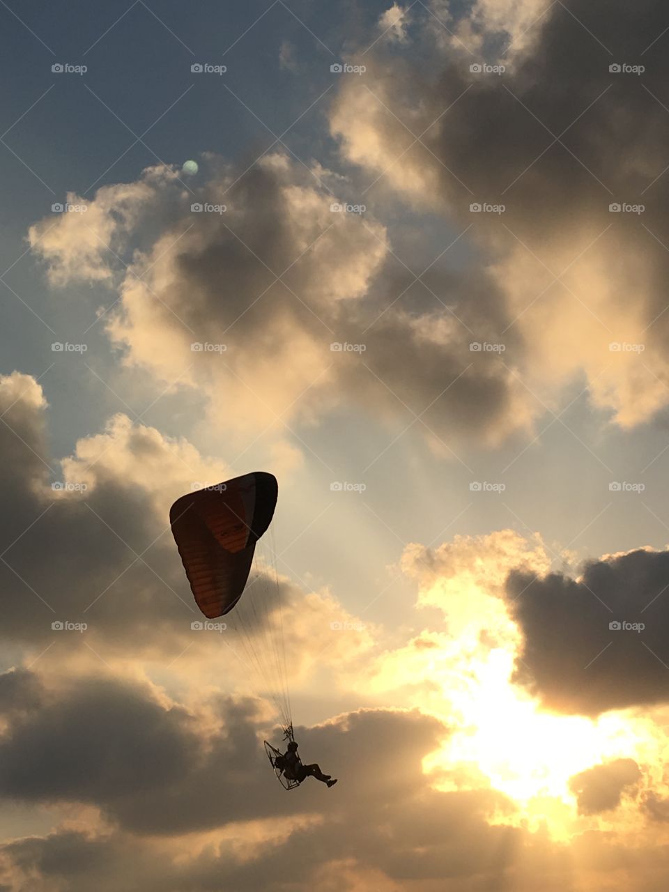 Paraglider floating through the sunset