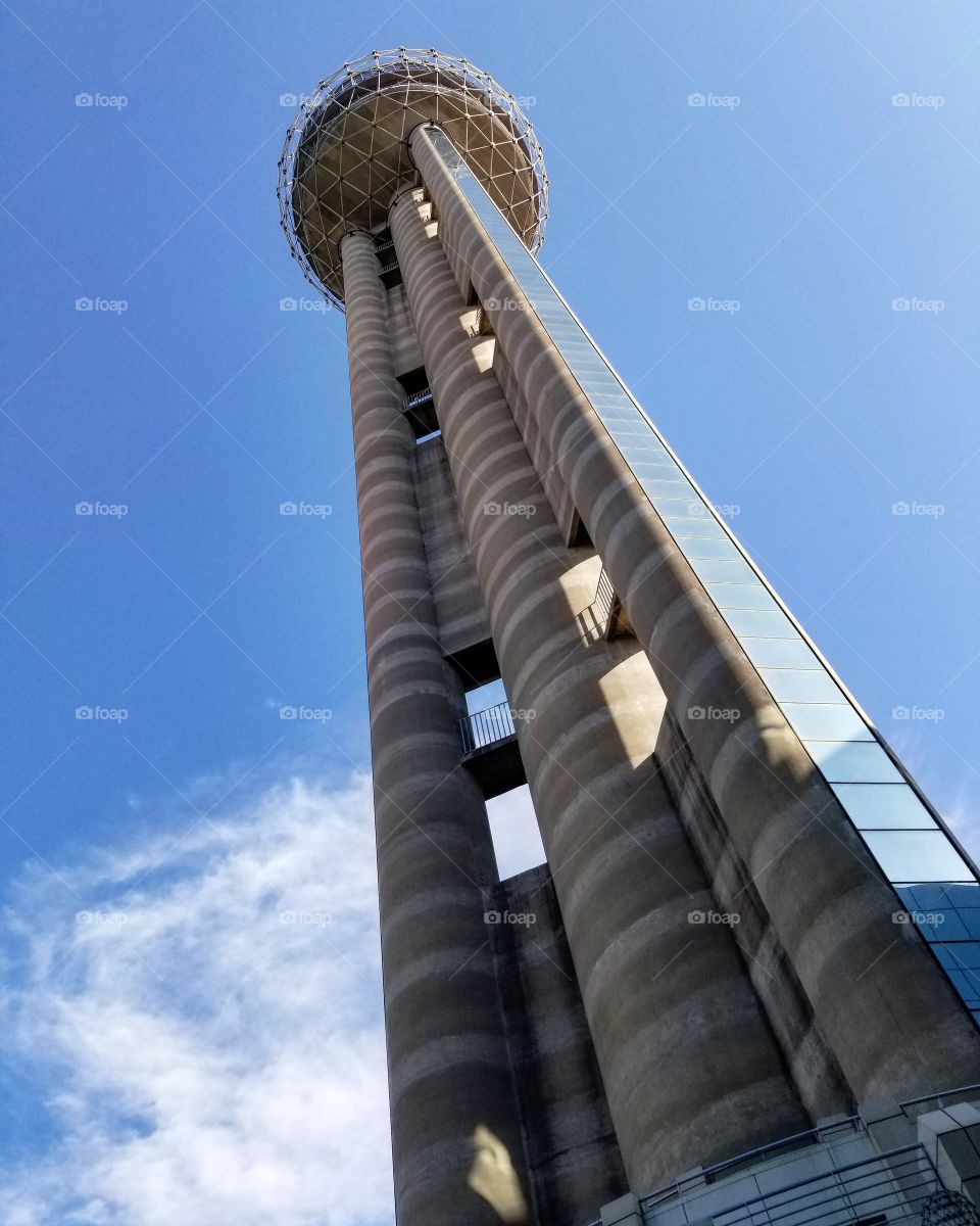 Tall concrete tower with ball on top against blue sky midday as seen from the ground