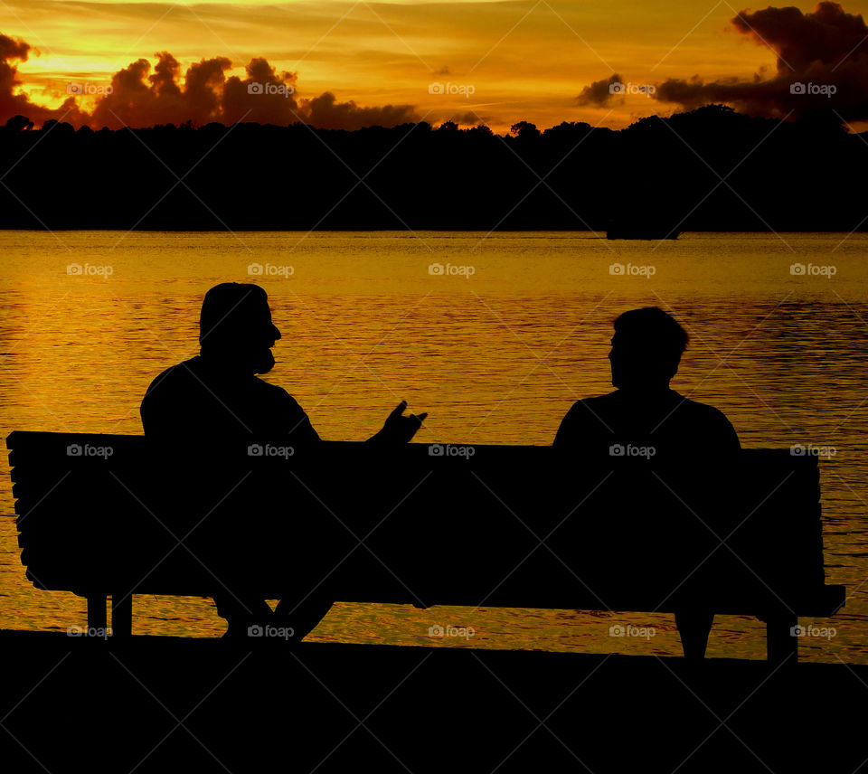 Silhouette of man sitting on bench during sunset