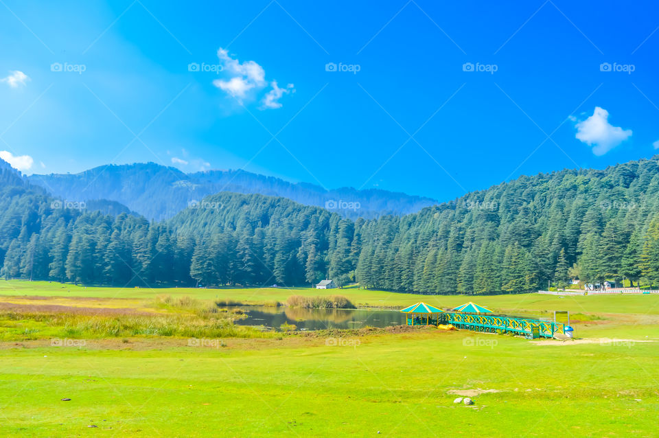 A beautiful golf course on a hill station with road blue sky trees clouds. Captured in sunny day hill station India taken landscape style useful for background wallpaper screen saver Vacation Concept