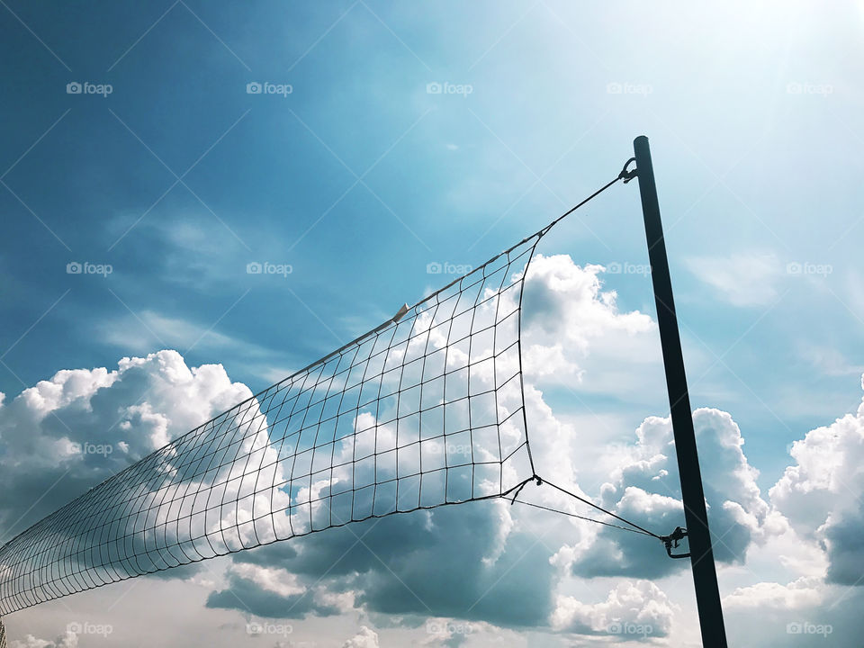 Beach basketball net in front of blue cloudy sky 