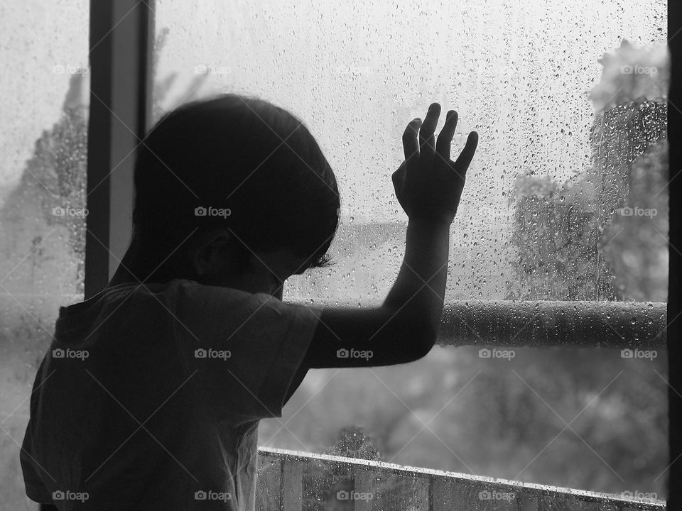 A sad boy stands near balcony window and feeling sad while outside heavy rain 🌧