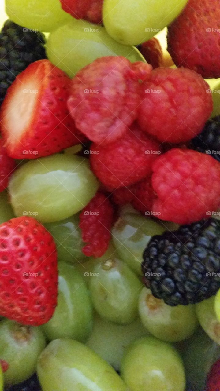 Fresh fruit variety that includes green grapes, strawberries, raspberries, and blackberries