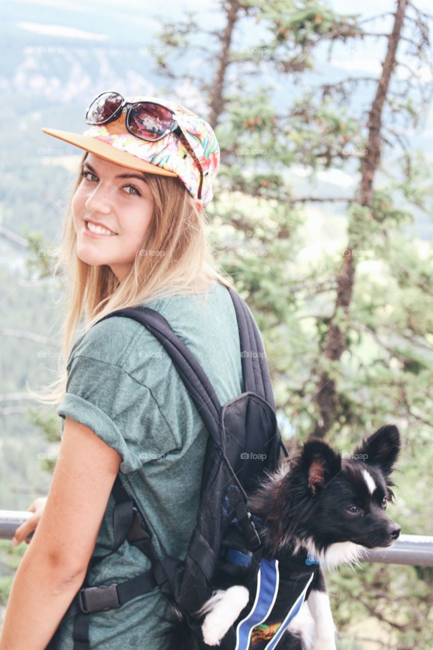 Smiling woman carrying dog in backpack