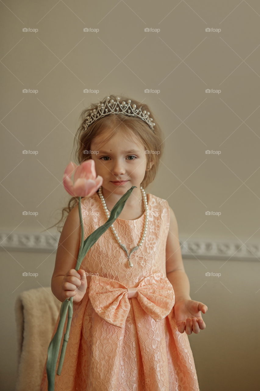 Vintage portrait of a beautiful little girl in pearl crown with tulip flower