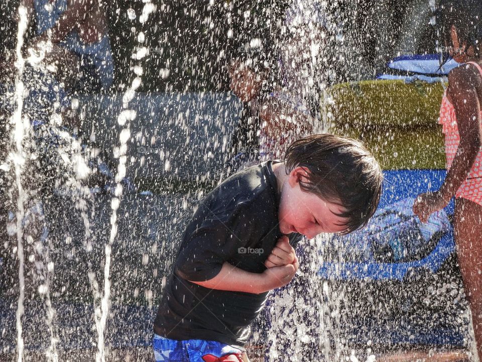 Splashing In A Water Fountain. Cooling Off In A Heat Wave

