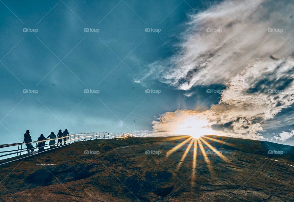 Nature photography - about to Sun set behind a mountain  - people climbing the top to have a beautiful view 