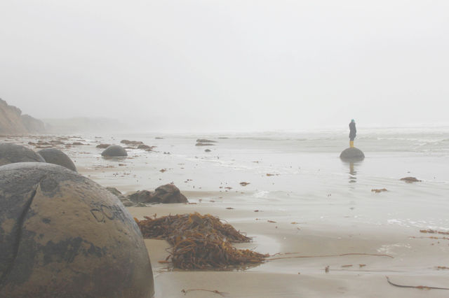 People standing on rock at foggy beach