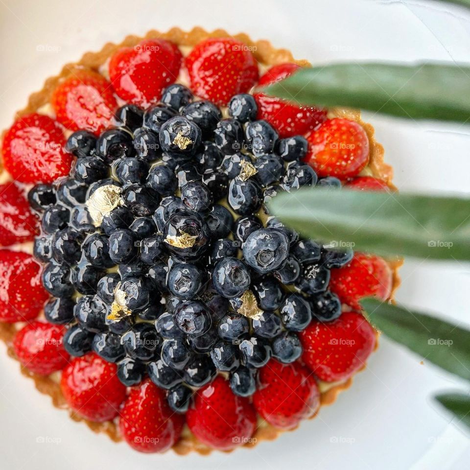 Strawberry blueberry fruit tart in custard and cake batter 