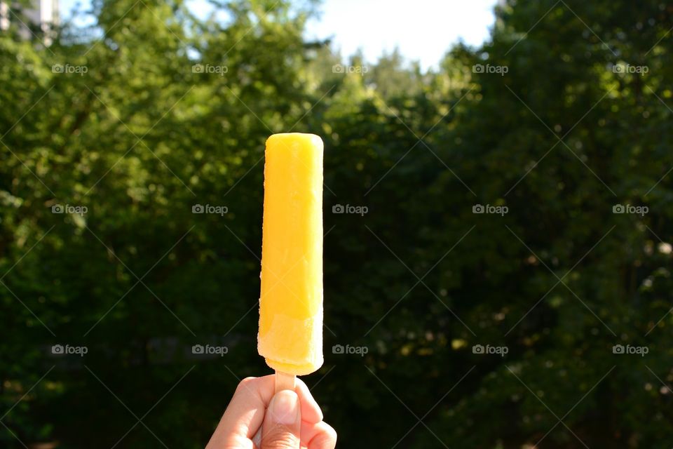 Banana ice cream in the hand green summer background