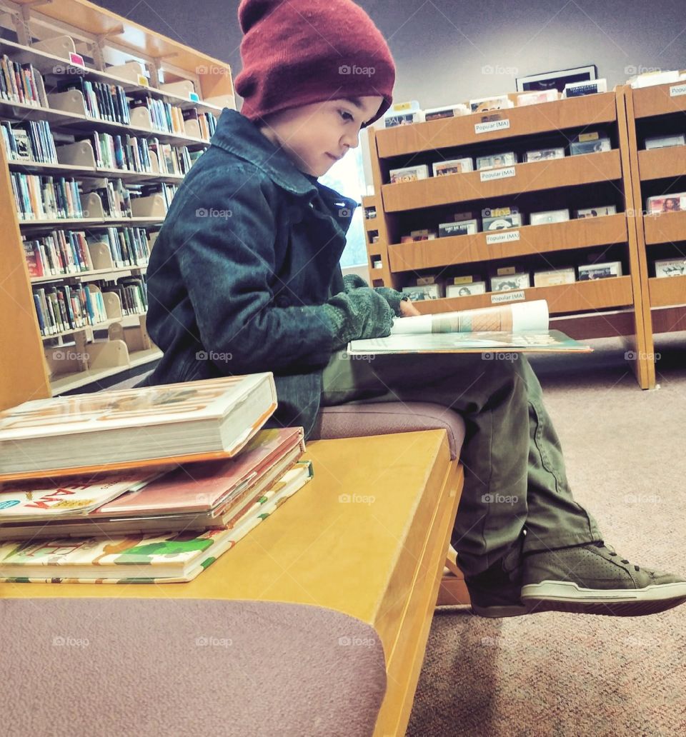 Young boy reads at library