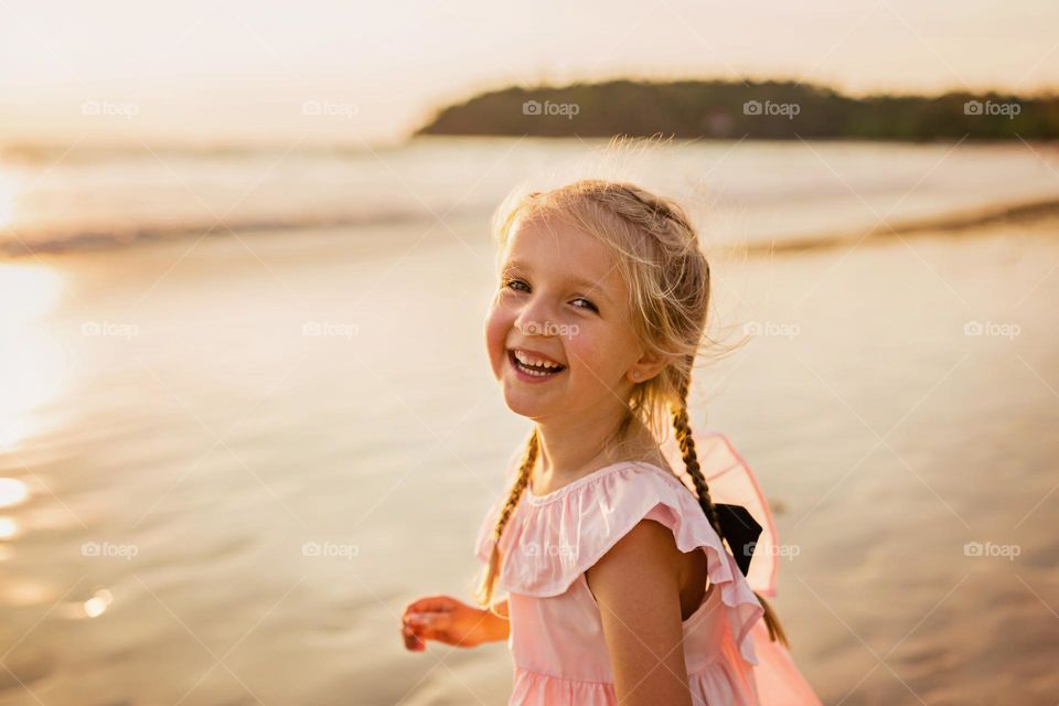 Candid lifestyle portrait of happy little Caucasian girl on beach 