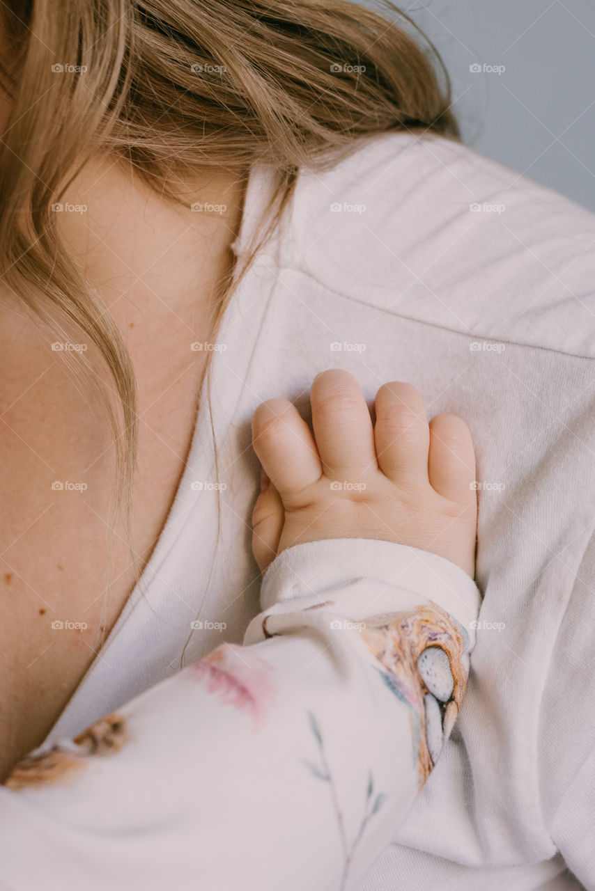 Baby’s handing resting on her mother. Calm motherhood moment.